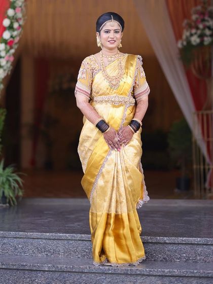 A full-length view of bride Rashmi's stunning Muhurtham attire. The saree is draped to perfection, and her entire look is one of grace and traditional elegance.