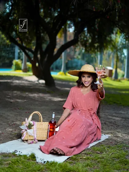 Creating a dreamy, picnic-themed scene for a summer dress campaign. The model is styled with a wicker basket and a glass of rosé, perfectly matching the relaxed, sunny-day mood.