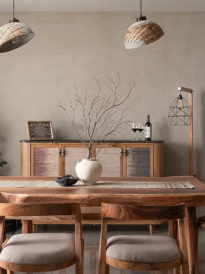 This dining room embodies a Wabi-Sabi aesthetic, celebrating natural imperfection. The walls are finished with a soft limewash, creating a beautiful backdrop for the custom live-edge dining table. The crockery console features unique shutters made from banana fibre, and concrete cane pendants add warmth and texture.