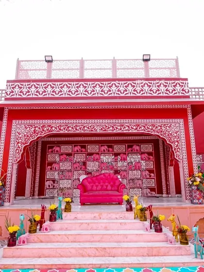 The main stage for a Rajasthani-themed Mehendi, featuring a vibrant pink sofa set against a backdrop of intricate jaali work and a wall of pink elephant figurines.