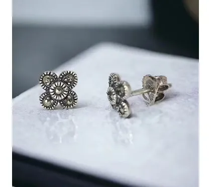 A pair of small, vintage-style studs with intricate marcasite detailing in a four-leaf clover pattern.