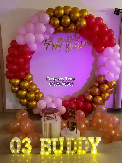 A red, white, and gold circular balloon arch for a 3rd birthday.