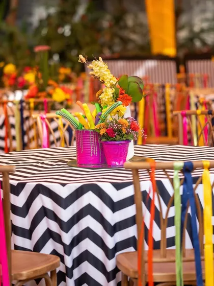 A close-up of the carnival-themed table setting, with a black-and-white chevron tablecloth and chairs adorned with multi-colored ribbons.