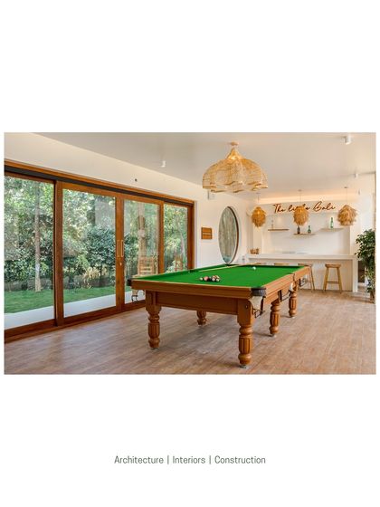 The entertainment room features a classic pool table and a minimalist bar area, with large sliding glass doors that open directly to the garden. It’s a space designed for leisure, blending indoor comfort with the beauty of the outdoors.