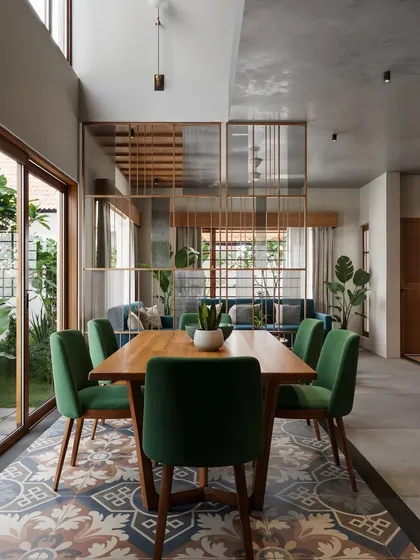 An open-concept dining area that showcases a mix of materials and patterns. The space is defined by traditional patterned floor tiles, which contrast with the modern dining set and a semi-transparent wooden partition that subtly divides the dining and living areas without obstructing the view.