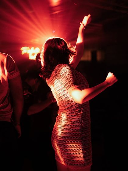 A beautiful silhouette of a woman dancing under a red spotlight.