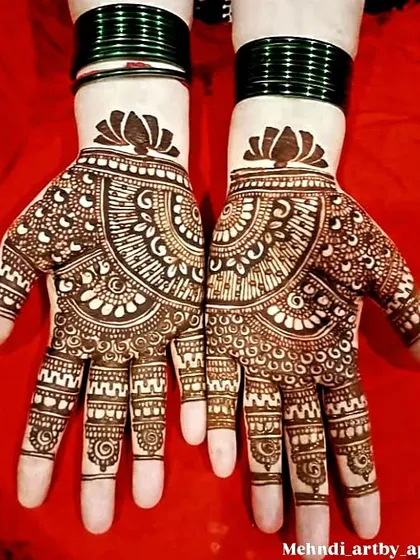 This is a classic party mehendi design that is always popular. The symmetrical semi-circular pattern is filled with detailed work and topped with a blooming lotus at the wrist for a balanced and beautiful finish.