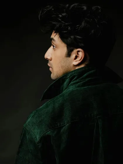A profile shot of Lakshya in a dark green corduroy jacket. This angle highlights the structure of the jacket and creates a classic, cinematic mood.