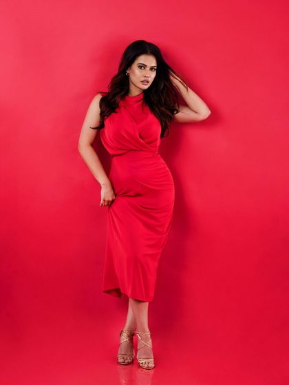 A vibrant studio portrait of actress Sharmiela Mandre. The bold red background makes the subject pop, creating a classic and eye-catching image.
