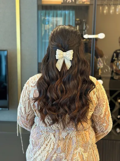 A sweet and feminine half-up style with soft waves, finished with a large, sparkly bow accessory. This is a fun choice for a baby shower or birthday party.