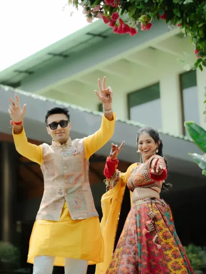 The couple dancing with joy, their hands in the air, perfectly capturing the fun and carefree spirit of their Haldi.