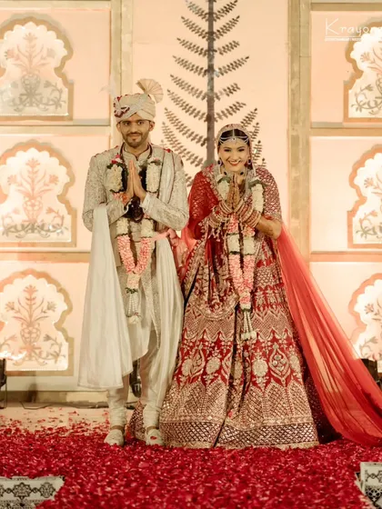 The newly married couple greets their guests with folded hands, a gesture of gratitude and respect, their faces beaming with joy.