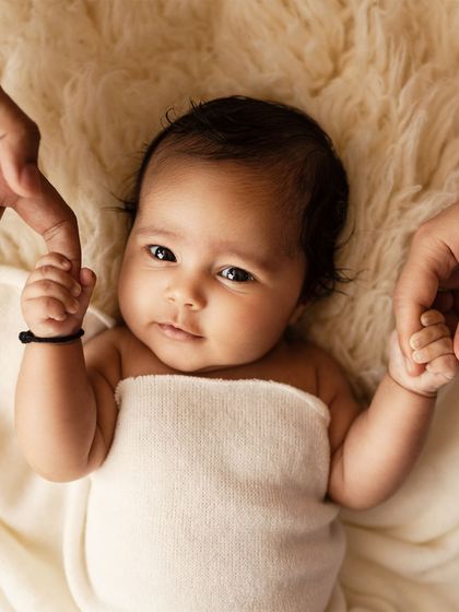 A similar concept, focusing on the baby's direct gaze as they hold their parents' hands.
