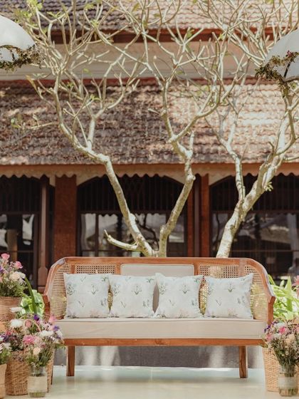 A closer look at the Mehendi stage seating, featuring a cane bench with custom-printed cushions and whimsical hanging umbrellas.