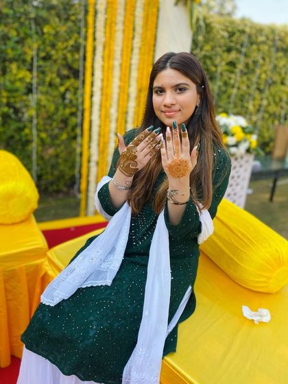 A happy client at a Haldi or Mehndi ceremony, showing off her simple yet elegant henna. This is a great example of party mehndi for guests.