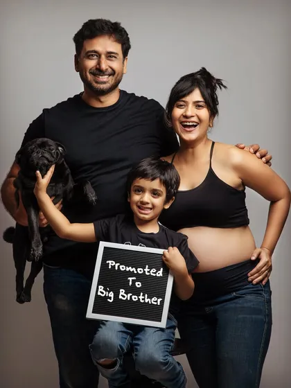 The whole family is excited! We absolutely love when siblings and even furry family members join the fun. This joyful family portrait with a "Promoted to Big Brother" sign is a perfect way to announce your growing family.