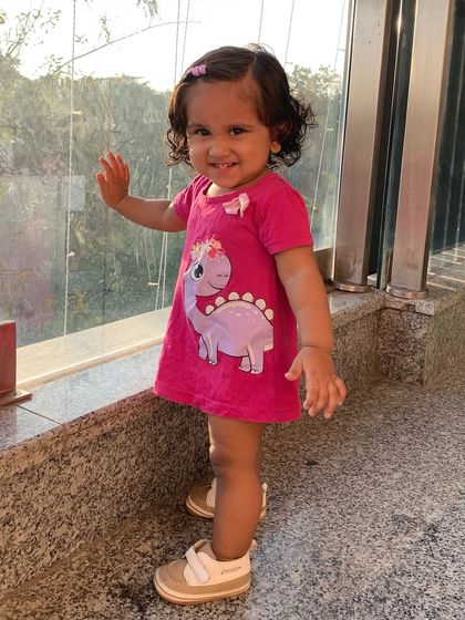 My daughter looking stylish in a pink dinosaur-print dress from Babyhug. It's a fun and casual outfit for her playtime.