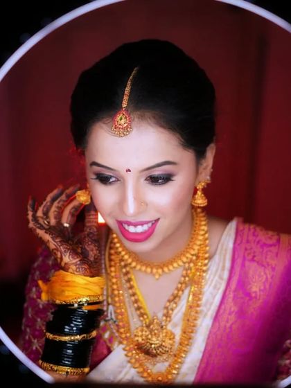 A candid moment of the bride checking her final look in the mirror. Her makeup is perfect for her muhurtham, with a soft pink eyeshadow and traditional gold jewellery.