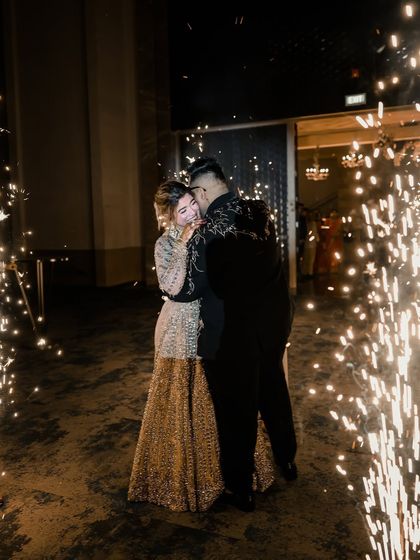 A candid, happy moment between a couple at their reception. The sparklers create a magical atmosphere, and the bride's joy is palpable.