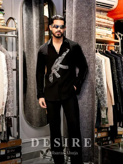 Dressed to thrill. This full-length shot shows the gun-embroidered shirt as part of a sleek, all-black ensemble that is pure power.