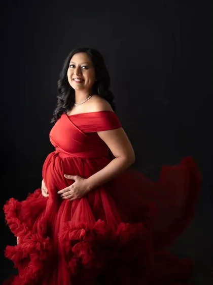 A radiant solo portrait of the mom-to-be. She looks so happy and confident in this incredible red ruffled gown. The simple black background really makes her and the dress the star of the show.
