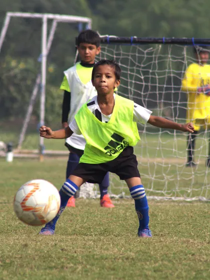A young player in a bib prepares to receive a pass, showing his readiness and focus.