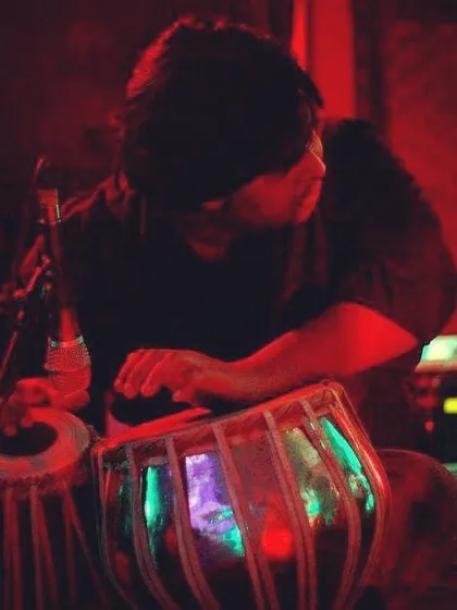 An atmospheric shot from a dimly lit stage, with intense red lighting. This photo captures the focused and introspective side of a live performance.