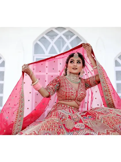 A bride poses in her stunning red lehenga against the clean white architecture of our modern set. The contrast makes the bridal attire pop, creating a powerful and beautiful portrait.