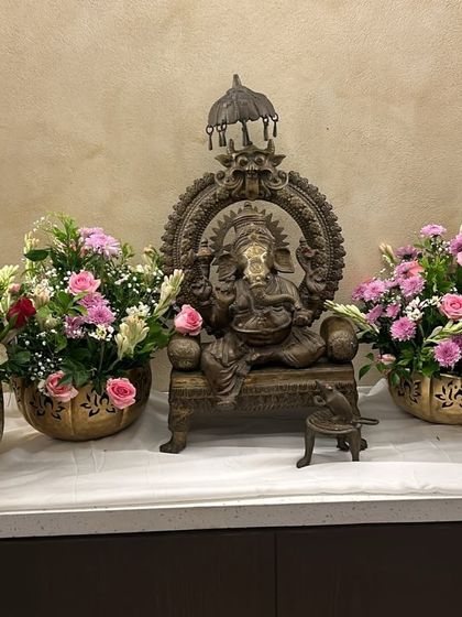 Floral arrangements are key to setting a festive mood. Here, a Ganesha idol is flanked by beautiful bouquets, perfect for a reception or wedding event entrance.