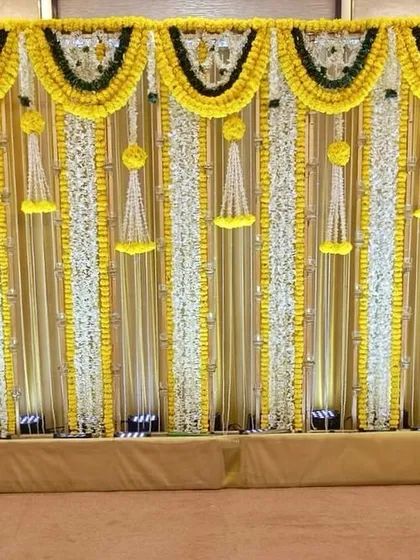 A simple yet elegant backdrop for a Mandap Mahurat Puja. The design uses curtains of white and yellow flowers, creating a sacred and beautiful space for the ceremony.