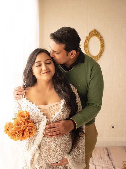 A sweet kiss on the forehead during a cozy, natural light maternity session. The lace robe and soft lighting add to the romantic feel.