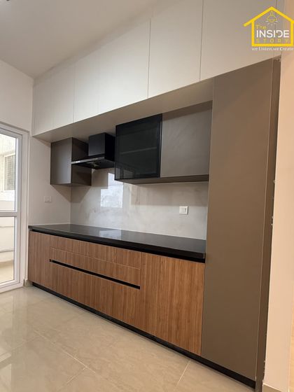 A clean and balanced parallel kitchen design. We used a mix of wood-finish and solid grey laminates with handleless drawers for a minimalist aesthetic that is easy to maintain.