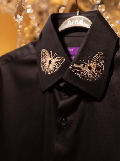 This black shirt is elevated with delicate, gold-thread butterfly embroidery on the collar. It's a subtle, sophisticated way to express your individual style.
