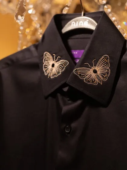 This black shirt is elevated with delicate, gold-thread butterfly embroidery on the collar. It's a subtle, sophisticated way to express your individual style.