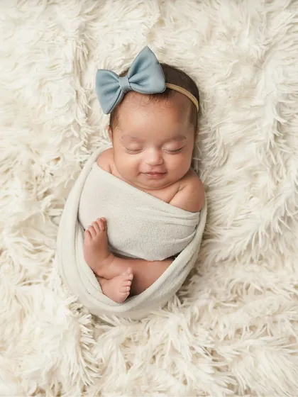 Sometimes, the simplest portraits are the most powerful. This image captures the pure serenity of a sleeping newborn, with a tiny smile that hints at sweet dreams. My newborn sessions focus on these peaceful moments, creating classic, beautiful infant portraits.