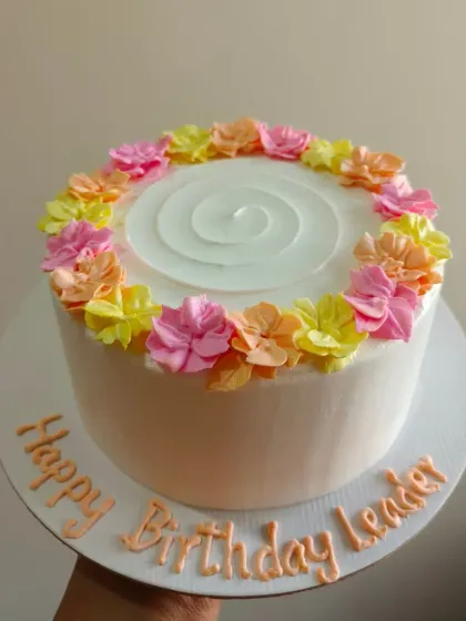 A simple and cheerful floral cake with a ring of colorful flowers, perfect for celebrating a team leader.