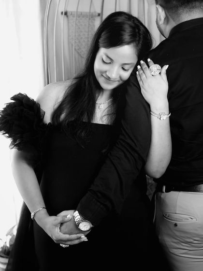 This black and white shot captures a candid, loving embrace. The way she holds onto his arm while cradling her bump creates a feeling of safety and partnership.
