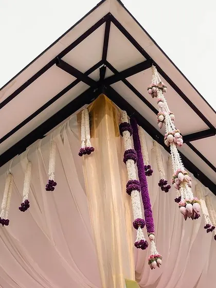 A detail of the mandap ceiling, with delicate floral strings hanging down. These small touches add texture and beauty to the overall design.