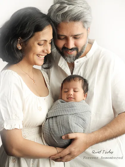 There is a special kind of peace in the first few weeks with a newborn. This portrait uses soft, light colors and a simple setting to highlight the serene, loving atmosphere as new parents cherish their sleeping baby.