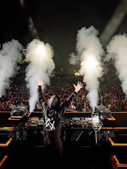 Alan Walker, arms raised in triumph, stands before a sold-out crowd in Kochi, surrounded by CO2 smoke.