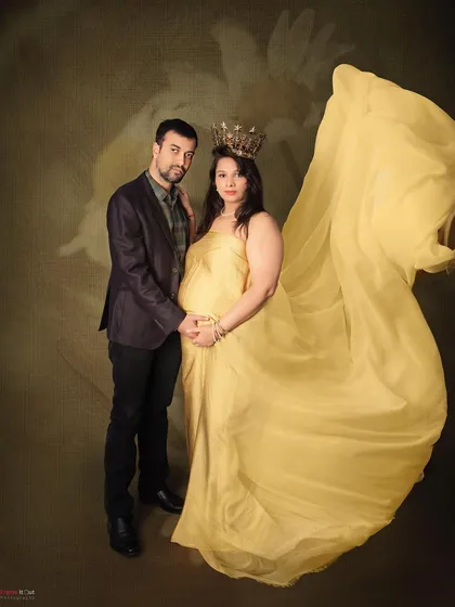 A royal portrait for a queen. The golden-yellow gown and crown create a majestic look, while the fabric toss adds a touch of dynamic energy to this stunning maternity photo.
