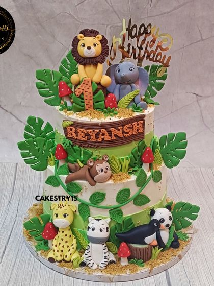 A wild two-tier jungle-themed cake for a first birthday. This 3kg chocolate cake is filled with fondant animals like a lion, elephant, panda, and giraffe.