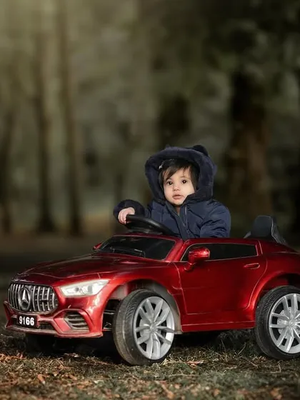 A cozy and cute driver in his hooded jacket. This little one is ready for a cool-weather adventure in his shiny red toy car.