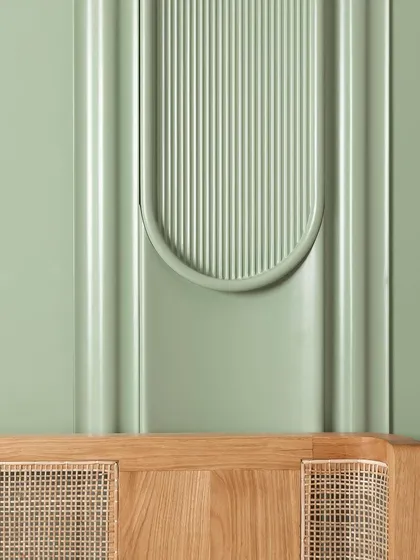 Lines and forms in harmony. The gentle curve of the fluted paneling on this sage green wall complements the natural grain and woven cane of the oak headboard below, creating a composition that is both soothing and visually interesting.