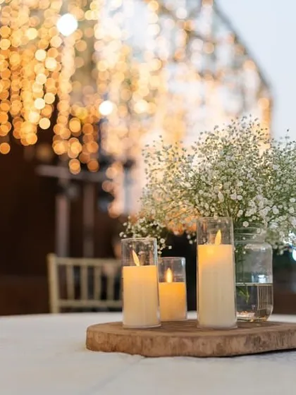 A close-up of a table centerpiece, featuring candles on a wooden slice, perfect for a rustic-chic reception.