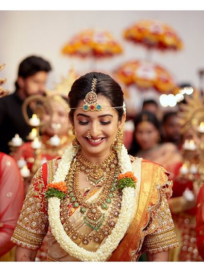 The radiant bride, captured in a moment of serene happiness. Her traditional attire and the grand temple setting come together to create a timeless bridal portrait.