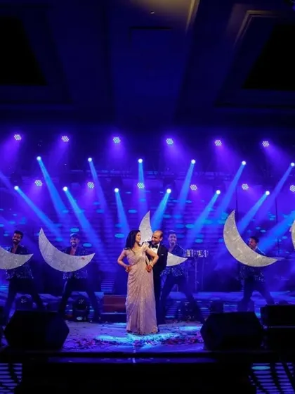 Creating a dreamy landscape on stage. For this couple's performance, we used giant moon props held by backup dancers to frame them, adding a touch of celestial magic to their sangeet act.