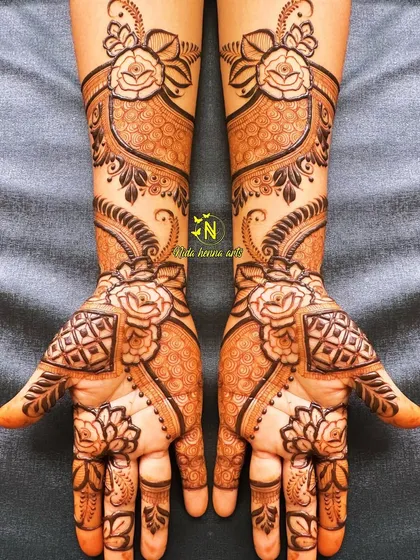 This design is all about floral work. It features large rose motifs on both the palms and the arms, connected by delicate patterns to create a cohesive and romantic look.