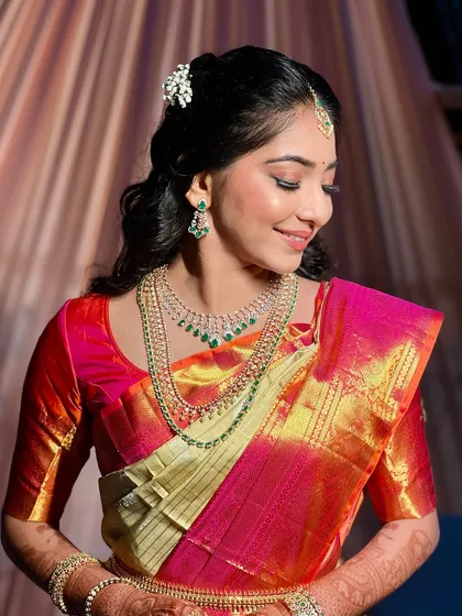 I love creating timeless looks for South Indian brides and guests. This style features gentle waves pulled back into a half-updo, accented with a traditional floral accessory. The makeup is kept fresh and radiant to complement the vibrant silk saree.