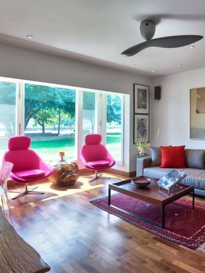 The study and television lounge at Aishbagh is a room designed for pause and repose. Comfortable seating, including vibrant pink armchairs, is paired with curated artwork and soft materials to create a space that adapts from quiet mornings with a book to late-night movie watching.